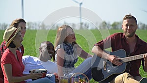 Friends arranged a picnic with songs and food on a green meadow, slow motion