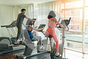 Friends athletes doing exercises together on gym machines in fitness center. Workout, sport, lifestyle concept