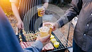 Friends and bbq party hold a plastic beer mug to celebrate the New Year holidays