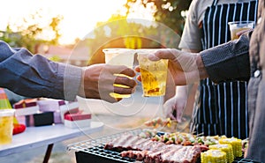 Friends and bbq party hold a plastic beer mug to celebrate the New Year holidays