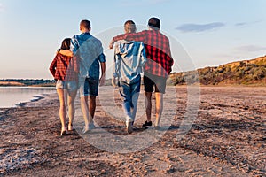 Friends on beach together walking during sunset