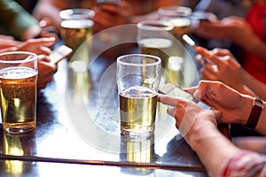 Friends with beer and smartphones at bar or pub