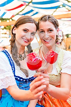 Friends in a beer tent holding candy apples