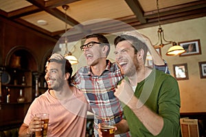 Friends with beer watching sport at bar or pub