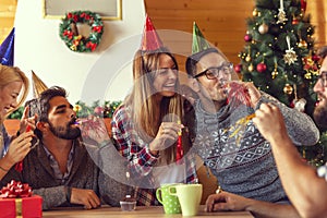 Friends blowing party whistles while celebrating birthday at home