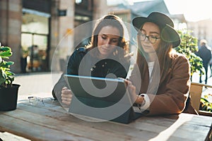 Friends businesswoman communication using digital tablet together. Girls hipster travels in Barcelona sitting in cafe. Business