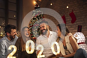 Friends celebrating New Year holding illuminative numbers 2020 photo