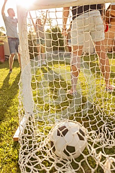 Friends celebrating scoring a goal while playing football in the backyard