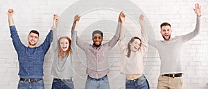 Friends celebrating succeess with raised hands over white wall