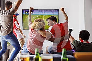 Friends cheering while watching football on TV