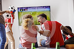 Friends cheering while watching football on TV