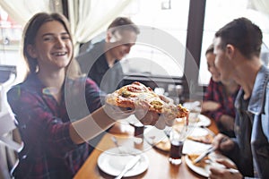 Friends of classmates eat pizza in a pizzeria, students at lunch eat fast food