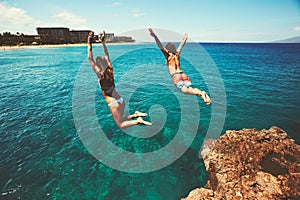 Friends cliff jumping into the ocean