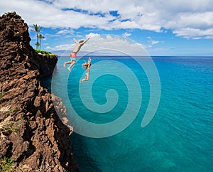 Friends cliff jumping into the ocean