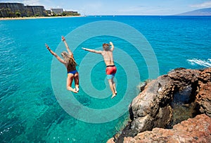 Friends cliff jumping into the ocean