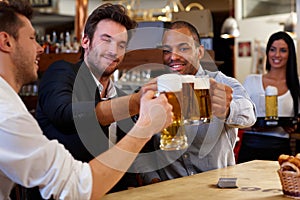 Friends clinking with beer mugs in pub