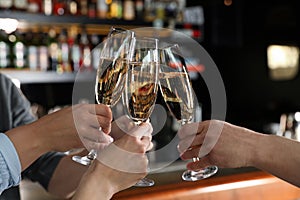 Friends clinking with glasses of champagne in bar