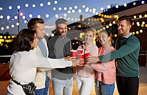 Friends clinking party cups on rooftop at night