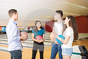 Friends Communicating While Having Fun At Bowling Alley