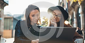 Friends communication using digital tablet together. Two girls hipster travels in Barcelona sitting in cafe. Business startup