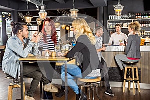 Friends Conversing While Sitting At Table In Bar