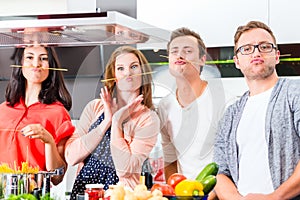 Friends cooking pasta and meat in domestic kitchen