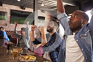 Friends At Counter In Sports Bar Watch Game And Celebrate