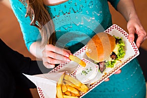 Friends or couple eating fast food with burger and fries