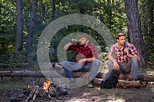 Friends couples enjoy vacation or weekend forest. Happy friends on a camping trip relaxing by campfire. Company two male