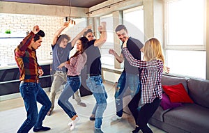 Friends dance at a student`s party in the apartment.