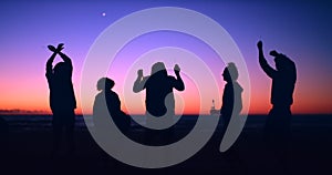 Friends, dancing and silhouette at night by beach, freedom and bonding together to relax for sunset outdoor. Men, women