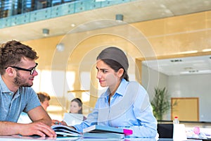 Friends discussing over book at table in library