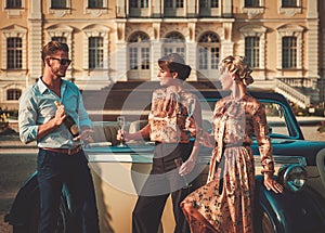 Friends drinking champagne near classic car