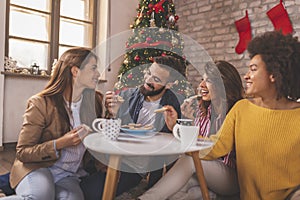 Friends drinking coffee and eating cookies on Christmas day