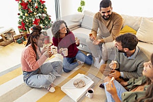 Friends drinking coffee and eating gingerbread cookies while celebrating Christmas