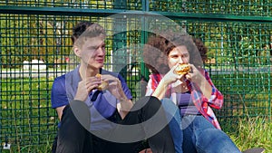 Friends eating burgers on sports ground