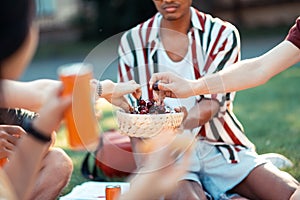 Friends eating cherries during their summer picnic.