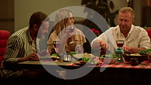 Friends eating meal during dinner. Men and woman talking at dining table