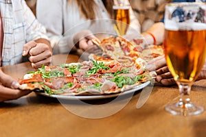 friends eating pizza with beer at restaurant