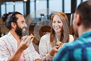 Friends eating pizza with beer at restaurant