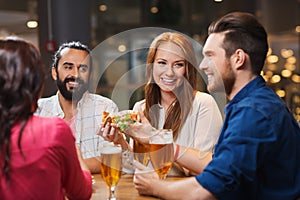Friends eating pizza with beer at restaurant