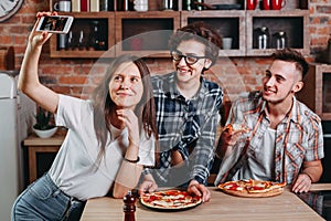 Friends eating pizza and taking selfie at party