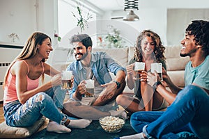 Friends eating popcorn and drinking beer mug at home, having fun