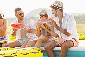 Friends eating watermelon at swimming pool party