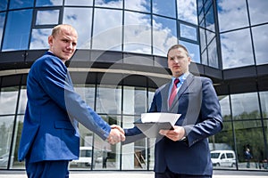 Friends in elegant business suits handshaking outdoors