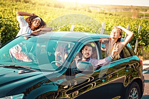 Friends enjoying a summerâ€™s road trip together countryside. Women and man driving smiling and looking out of window