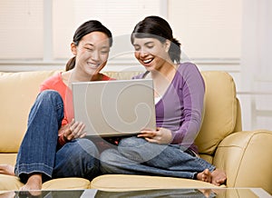 Friends enjoying using the laptop on sofa
