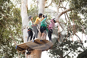 Friends enjoying zip line adventure in park