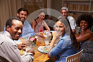 Friends at an evening dinner party, looking at camera