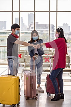 friends with face mask fist bump in airport terminal